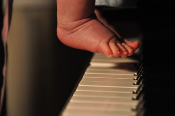 The child's foot presses the piano keys