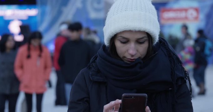 Womans types on smartphone outdoors on cold winter day - medium shot