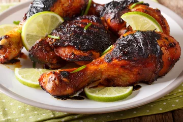 Foto op Canvas Jamaican food: jerk chicken drumstick with lime closeup on a plate. horizontal © FomaA