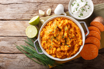 Freshly prepared mashed sweet potatoes with herbs, garlic and lime close up in a pot. horizontal...