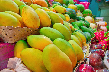 Concept street trade exotic fruits. Tropical fruits on counter of a street shop. Ripe yellow mango and dragon fruit.
