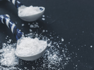 White salt in spoon on black background