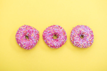 Sprinkled Pink Donut. Frosted sprinkled donut on yellow background.