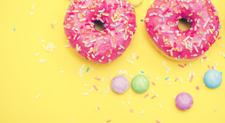 Pink Donut with sprinkles on yellow background 
