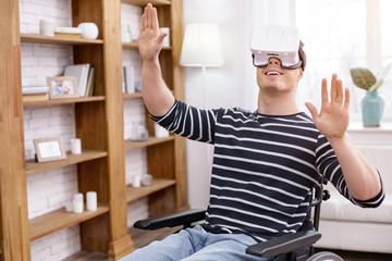 Want to fly. Cheerful invalid keeping smile on face and raising arms while being frustrated