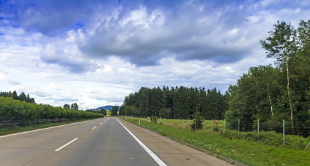 Austrian highway number 3 (autobahn) near Passau in summer weekend evening. Shooting from the bus at the beginning of the rain, traces of which are visible on the glass