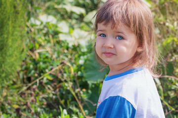 Cute baby girl with blonde curly hair outdoors. Little girl 2-3 year old.