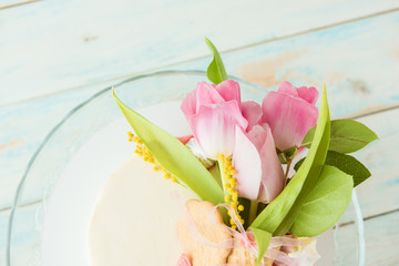 Bouquet of pink tulips on a white biscuit cake