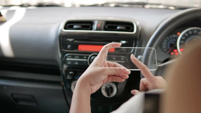 Hands of woman using clear tablet in a car for transport futuristic and technology concept 