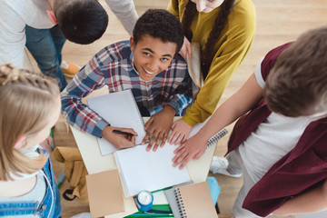 high angle view of high school students helping their classmate with homework