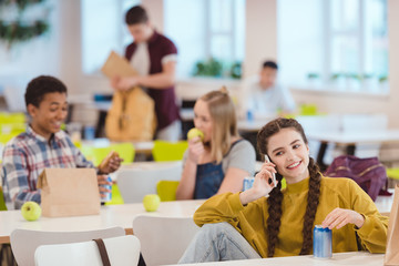 happy teen schoolgirl talking by phone at school cafeteria