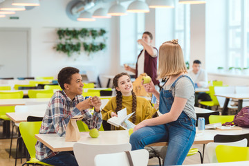 happy high school students taking lunch together at school cafeteria - Powered by Adobe