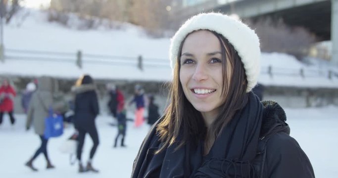 Young woman on rideau canal during winter festival - turns to look and smile at camera