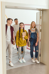 happy teenage high school students walking by school corridor