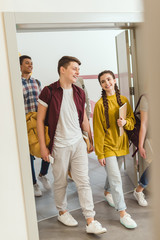 multiethnic group of high school students walking by school corridor on break