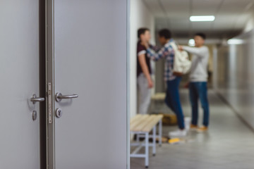 blurred shot of schoolboy being bullied by classmates in school corridor