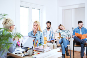 Beautiful young confident girl is having a job interview while others are waiting patiently.