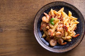 Shrimp pasta with sun dried tomatoes and basil in creamy mozzarella sauce. View from above, top studio shot