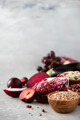 Ingredients for cooking, copy space, top view, flat lay. Purple vegetables, fruits on grey background. Violet eggplant, beets, cauliflower, purple beans, plums, onion, grape, quinoa, rice.