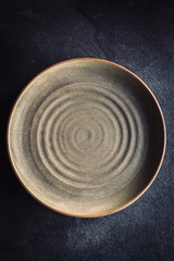 Empty ceramic and handmade plate o  the dark background
