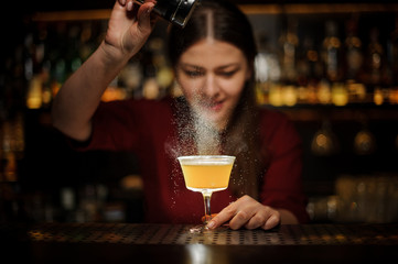 Smiling female bartender pouring a spice to the delicious cocktail