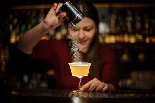 Female bartender pouring a spice to the fresh cocktail