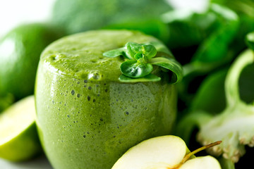 Glass with green health smoothie, kale leaves, lime, apple, kiwi, grapes, banana, avocado, lettuce. Copy space. Raw, vegan, vegetarian, alkaline food concept.