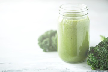 Glass jar mugs with green health smoothie, kale leaves, lime, apple, kiwi, grapes, banana, avocado, lettuce. Copy space, sunlight effect. Raw, vegan, vegetarian, detox, alkaline food concept.