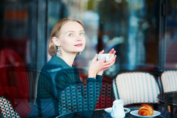 Young elegant woman drinking coffee in cafe in Paris, France