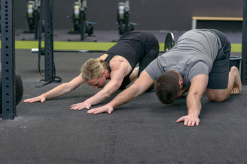 Man and woman stretching in a gym