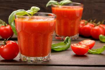 Tomato juice with vegetables and basil on wooden background