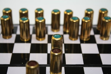 Brass bullets gun munition on black and white chessboard desk