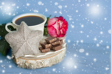 Hot coffee, pieces of chocolate and a rose flower. A festive breakfast.