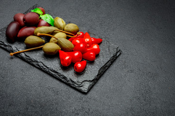 Mixed Pickles on stone serving board. Olives, Capers and peppers