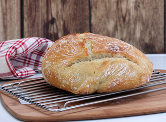 A loaf of fresh baked Artisan Bread on a cooling rack.