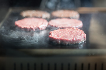 Hamburger cutlet frying on pan.Natural meet loaf pieces cooking in the kitchen.Burger sandwich meat being cooked with a lot of white smoke from a fat and oil.