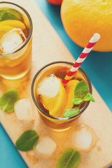 Glasses of iced tea with lemon slices and mint on turquoise wooden background. Toned