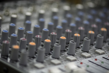 Close up of a mixing console with sliders and buttons.