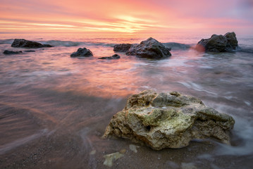 Sunrise with vibrant orange and red sky , rocks on foreground