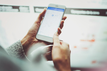 Female hand holding smartphone and using internet for looking new way on electronic city map with night modern blurred background.