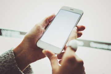 Girl holding smartphone with white empty screen in night atmospheric city.Closeup on blurred background.