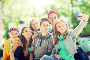 education, high school, technology and people concept - group of happy teenage students or friends taking selfie by smartphone