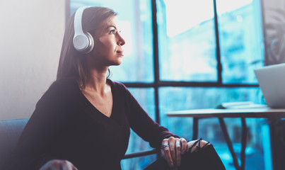 Beautiful blonde girl wearing eye glasses and casual clothes listening digital music in headphones...