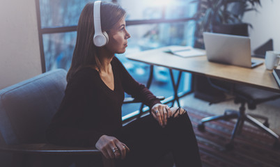 Beautiful blonde girl wearing eye glasses and casual clothes listening digital music in headphones...