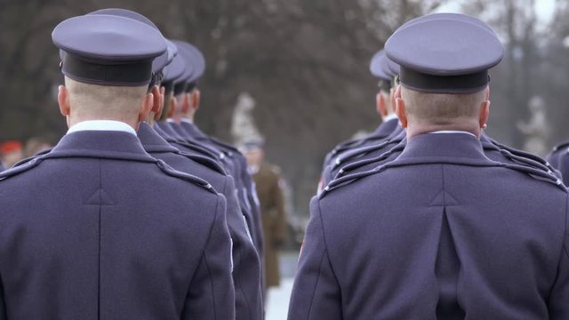 The commander gives awards to soldiers in blue uniform, soldiers stand with their backs to the camera. Camera without movement, in the foreground of the head of the soldiers.