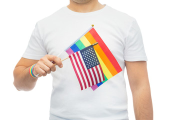 lgbt, same-sex relationships and homosexual concept - close up of man wearing gay pride rainbow awareness wristband and holding american flag