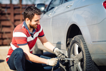 Fototapeta na wymiar Smiling man and mechanic changing tyres, using jack and wheel wrench