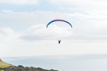 Paragliding. Ringstead Bay, Dorset / England. 02/15/2018. Paragliding pilots riding the wind off the cliffs of the Dorset Coast in training for the British Open Competitions in July. 