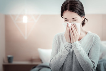 I must to struggle. Ill sad unsatisfied woman spending time in the bright room sneezing and closing...