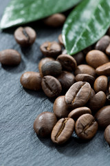 roasted coffee beans and leaves on a dark background, close-up